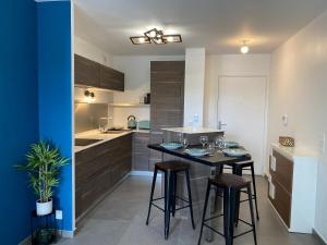 a kitchen with a table and stools in a room at Bel Appartement lumineux à 5 minutes d'Annecy in Seynod