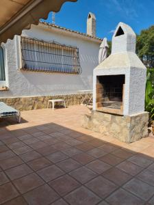 a patio with a stone fireplace in front of a house at maison nathalia in Jávea