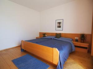 ein Schlafzimmer mit einem großen Holzbett mit einer blauen Decke in der Unterkunft Apartment zur schönen Aussicht in Algund