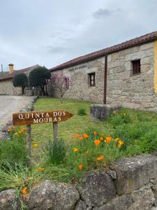 un panneau devant un bâtiment en pierre avec des fleurs dans l'établissement Quinta dos Mouras, à Castelbuono