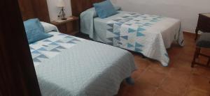 a bedroom with two beds with blue and white sheets at Casa Cueva El Almendro in Pegalajar