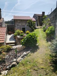 an old stone house with a garden in the foreground at Casa da Portela in Caminha