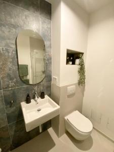 een badkamer met een wastafel, een toilet en een spiegel bij DOCK 12 - Exklusives Cityapartment in Bremerhaven