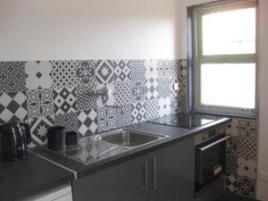 a kitchen with a sink and a tile wall at Les deux pentes in Sausses