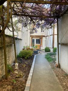 a walkway in front of a house with purple flowers at Appart' Au Coeur de Nuits in Nuits-Saint-Georges