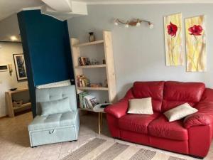 AL CLISI graziosa mansarda في Villanuova sul clisi: غرفة معيشة مع أريكة حمراء ورف كتاب