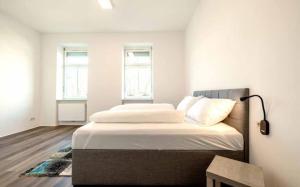 a bedroom with a bed with white sheets and two windows at City Apartments Amstetten in Amstetten