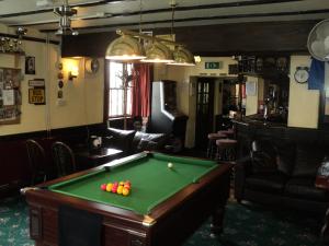 a room with a pool table and a chair at Ostler Inn in Uffculme