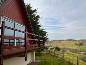 a red house with a balcony on the side of it at Highland Glen Lodges in Rogart