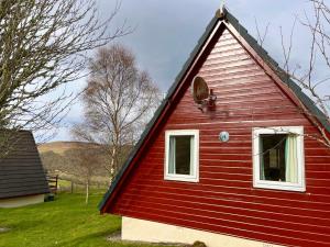 een rood huis met een raam en een dak bij Highland Glen Lodges in Rogart