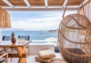 a room with a swing chair and a table and the ocean at Captain Zeppos in Pollonia