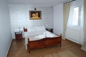 a bedroom with a bed with white sheets at Pensiunea Royal in Ranca