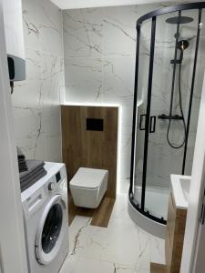 a bathroom with a shower and a washing machine at PM RESIDENCE KORFANTEGO 8 in Katowice