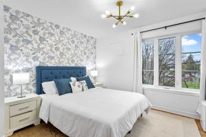 a white bedroom with a bed and a window at Le 900 Tremblant Inn Café and Bistro in Mont-Tremblant