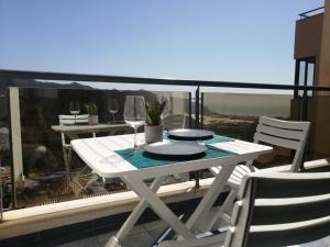 - une table et des chaises blanches sur un balcon avec des verres à vin dans l'établissement Apartamento Sierra y Mar, à La Envia