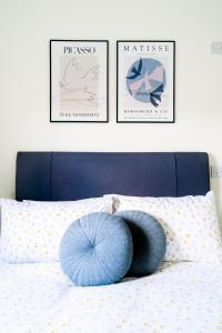 ein Bett mit drei Bildern und einem blauen Kissen darauf in der Unterkunft Elm Cottage at Gravel Farm in Stretham