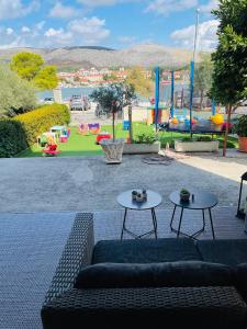 a couch and two tables with a playground in the background at Apartments Kapetanovi Dvori in Trogir
