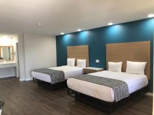 2 camas en una habitación de hotel con paredes azules en Cali Inn en Carson