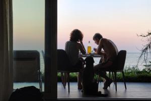 grupa trzech kobiet siedzących przy stole z psem w obiekcie Beach Villa Varna - cosiness 4 meters from the sea w Warnie