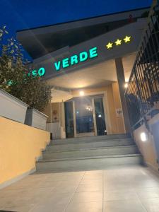 un panneau vert à l'avant d'un bâtiment la nuit dans l'établissement Hotel Paradiso Verde, à Marina di Bibbona