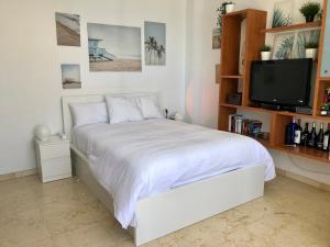 トレモリノスにあるApartamentos La Roca Costa del Solの白いベッドルーム(ベッド1台、テレビ付)