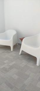 two white benches sitting on top of a tile floor at Maison de village au calme - Alonia Village House in Psinthos