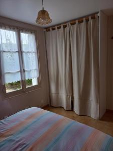 a bedroom with a bed and two windows at Perrot Henry in Saint-Marcouf