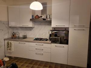 Una cocina con gabinetes blancos y un horno de estufa. en alloggio a 200mt. dal mare, en Diano Marina