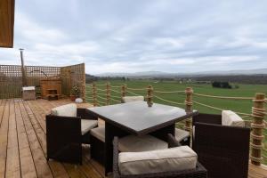 a patio with a table and chairs on a wooden deck at The Paddock- Loch Lomond and Trossachs in Gartmore