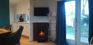 a living room with a fireplace with a tv above it at Chalet op mooie rustige plek in Enschede