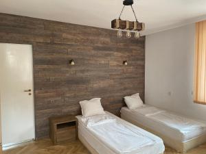 1 dormitorio con 2 camas y pared de madera en Guest House Simona en Sapareva Banya