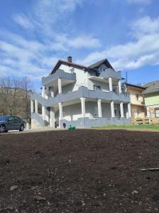 a large white building with a car parked in front of it at Prenoćište Ljiljana 2 in Livno