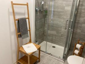 a bathroom with a shower and a table and a chair at Maria Trafaria House in Trafaria