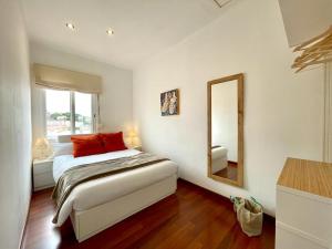 una camera da letto con un letto con un cuscino rosso e uno specchio di APARTAMENT MEDITERRANI a Canet de Mar