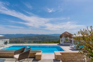 a swimming pool with two chairs and a gazebo at Alkiviades Villa in Theletra