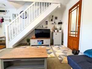 a living room with a tv and a staircase at 2 bedroom home in quiet location close to Chester in Hough Green