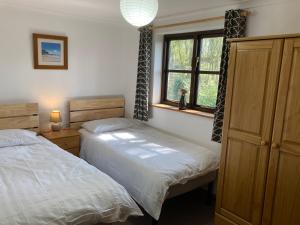 a bedroom with two beds and a window at Prince Croft Cottage in Porthtowan