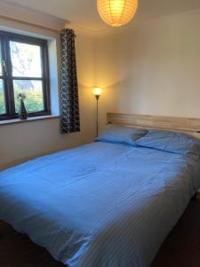 a bedroom with a large bed with a blue comforter at Prince Croft Cottage in Porthtowan