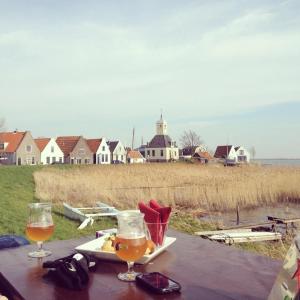 Una mesa con dos vasos de cerveza y un plato de comida. en Very nice cottage in Durgerdam, with private garden, free parking, pets allowed, en Ámsterdam