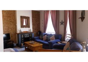 a living room with a blue couch and a tv at Driftwood Apartments Broadstairs in Broadstairs