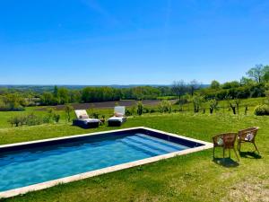 a swimming pool in a field with two chairs at La Vignerie in Boisse