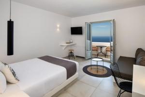 a hotel room with a bed, chair, and table at Seven Suites in Imerovigli
