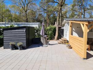 eine Terrasse mit einem Sonnenschirm und einem Schuppen in der Unterkunft Chalet Casablanca, totaal 80m2 met veel comfort op fantastisch 5-sterren vakantiepark! in Sevenum