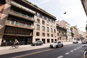 una persona montando una bicicleta en una calle de la ciudad con coches en MagnoliaApartments - 18B Visconti Duomo, en Milán