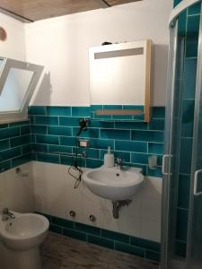 Appartamento Severino - Rariche House في كاميروتا: حمام مع حوض ومرآة ومرحاض