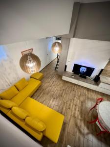 a living room with a yellow couch and a flat screen tv at Apartman Cvjetni in Njivice