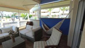 - une terrasse couverte avec un hamac et des chaises sur un balcon dans l'établissement Cabo Roig Calas de Campoamor Pádel y piscina con vistas al mar, à Orihuela Costa