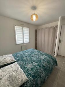 een slaapkamer met een bed met een blauwe en witte deken bij Maison de vacances in Léon