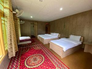 a room with two beds and a red rug at Tourist Cottage Hunza in Hunza Valley