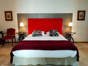 - une chambre avec un grand lit et une tête de lit rouge dans l'établissement Le Clos Bel Ami, à Bec-de-Mortagne